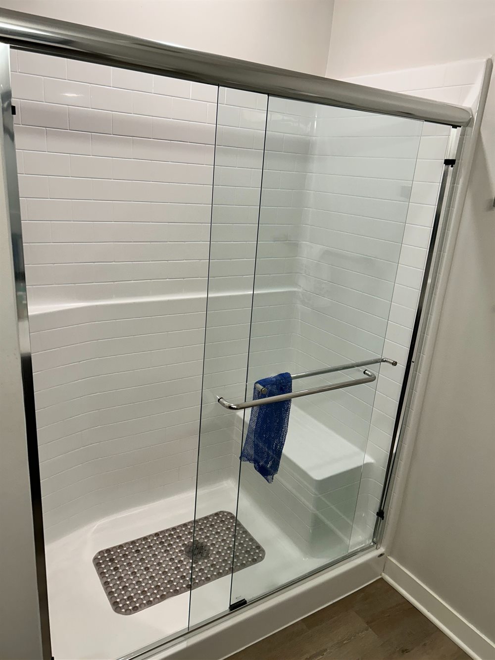 Spotless white tile shower with glass doors after a deep clean