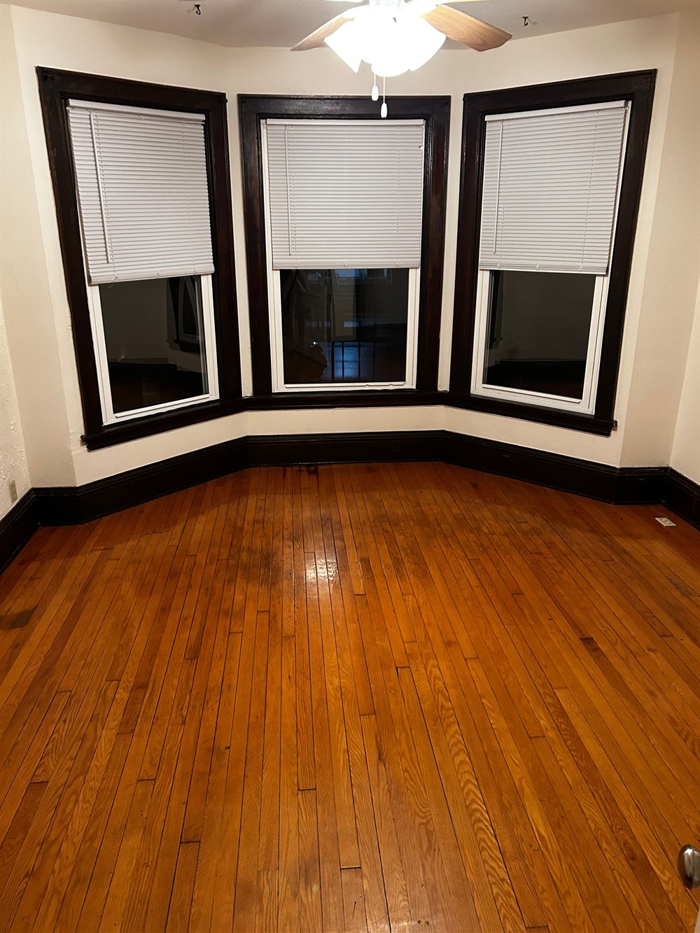 Empty room with bay windows and clean hardwood floors after a move-out clean