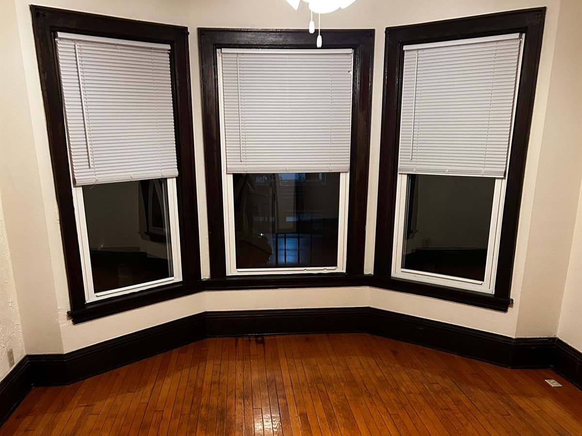 Emptied living room with bay windows and swept hardwood floors, ready for the final walkthrough
